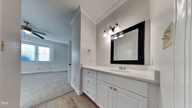 bathroom with wood-type flooring, crown molding, vanity, ceiling fan, and a textured ceiling