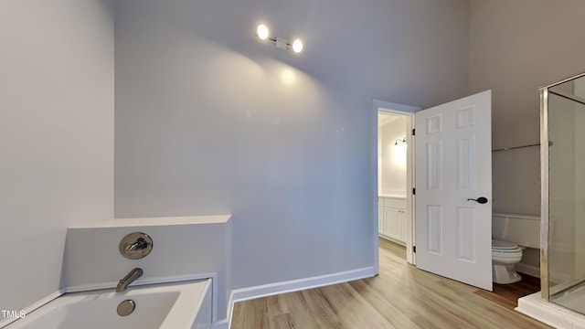 bathroom with toilet, shower with separate bathtub, and hardwood / wood-style floors