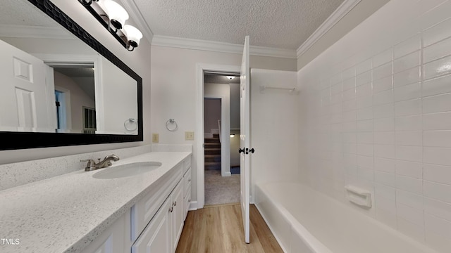 bathroom featuring wood-type flooring, vanity, a textured ceiling, and ornamental molding