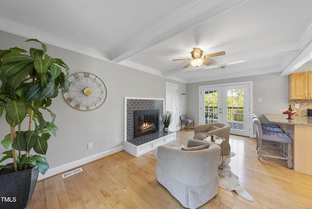 living room featuring ceiling fan, light hardwood / wood-style floors, beam ceiling, ornamental molding, and french doors