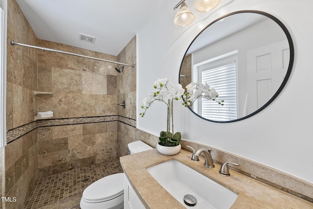 bathroom featuring toilet, vanity, and tiled shower