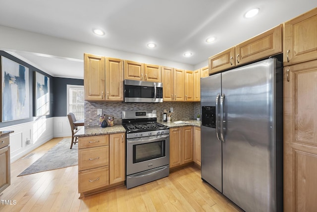 kitchen with light hardwood / wood-style floors, light stone countertops, backsplash, and stainless steel appliances