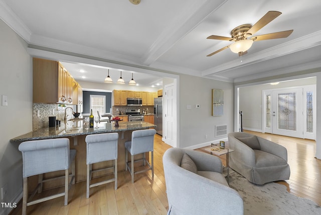 living room featuring ceiling fan, ornamental molding, beamed ceiling, and light wood-type flooring