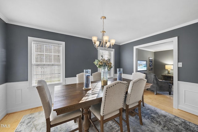 dining room with light wood-type flooring, crown molding, and a notable chandelier