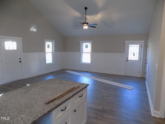 interior space with white cabinetry, light stone counters, ceiling fan, high vaulted ceiling, and dark hardwood / wood-style flooring