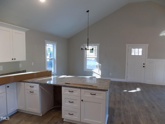 kitchen featuring hanging light fixtures, dark hardwood / wood-style flooring, light stone counters, white cabinetry, and lofted ceiling