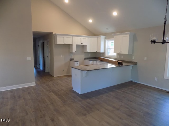 kitchen with kitchen peninsula, high vaulted ceiling, dark hardwood / wood-style floors, and white cabinetry