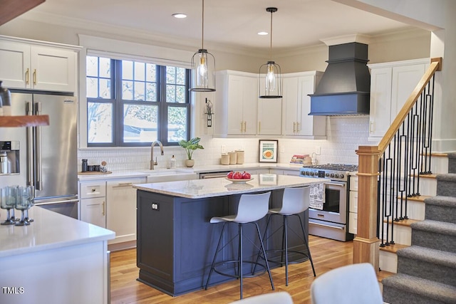 kitchen with white cabinets, custom exhaust hood, a kitchen island, hanging light fixtures, and high quality appliances