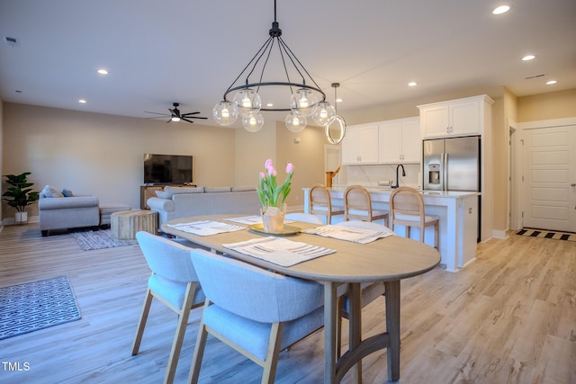 dining space featuring light wood-type flooring, ceiling fan, and sink