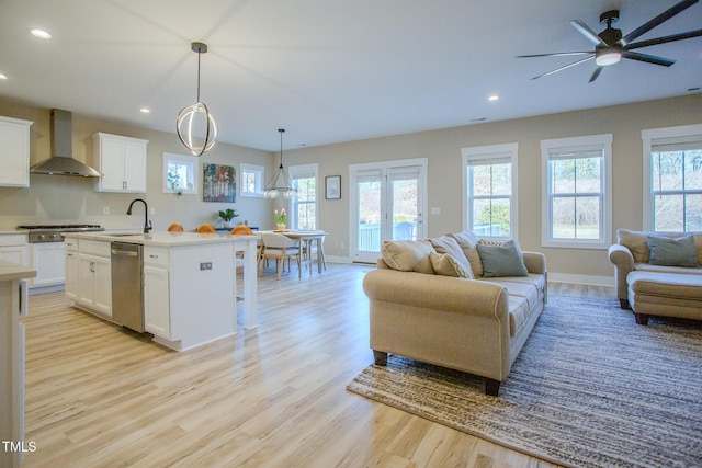 living room with ceiling fan, a wealth of natural light, light hardwood / wood-style flooring, and sink