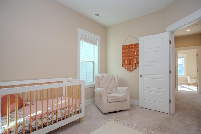 bedroom with light carpet, a nursery area, and multiple windows