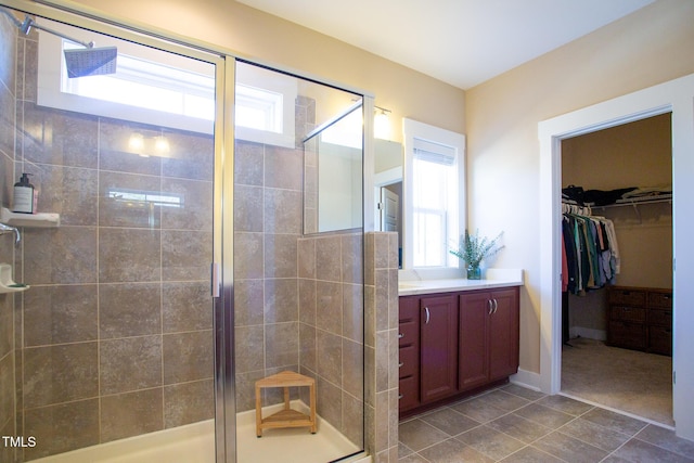 bathroom with a shower with shower door, tile patterned floors, and vanity