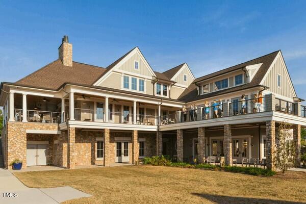 back of house with a lawn and a balcony