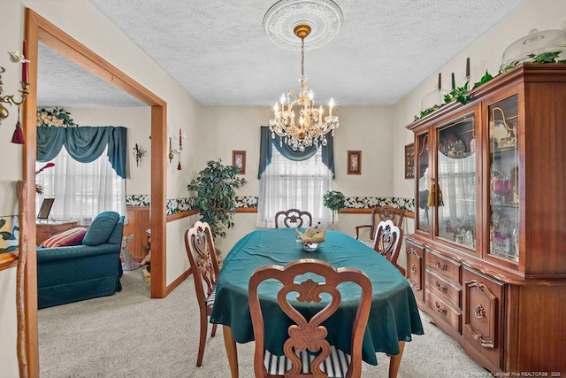 carpeted dining area with a textured ceiling and a chandelier