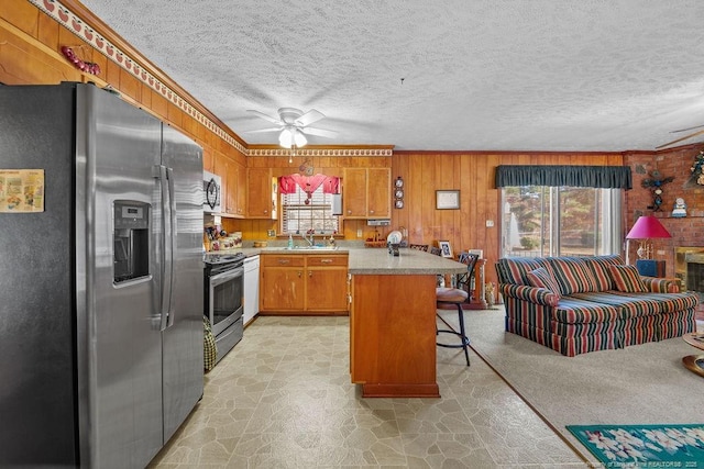 kitchen with stainless steel appliances, a center island, ceiling fan, a breakfast bar, and sink