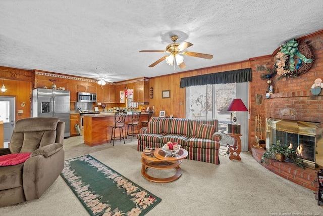 carpeted living room with a textured ceiling, wooden walls, and a fireplace