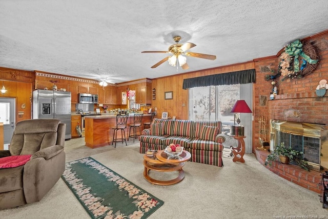 living room with ceiling fan, light carpet, wood walls, and a textured ceiling