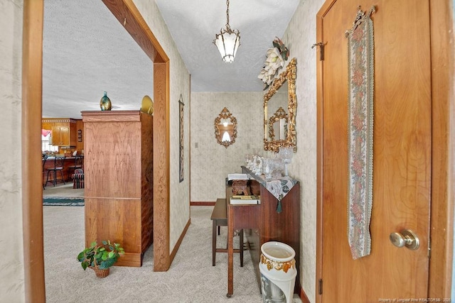 hallway featuring a textured ceiling and light carpet