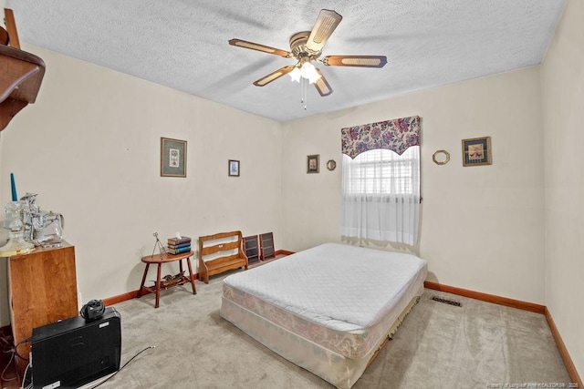 bedroom featuring a textured ceiling, ceiling fan, and light carpet