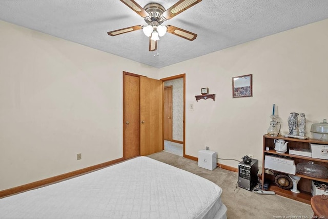 bedroom featuring ceiling fan, light colored carpet, and a textured ceiling