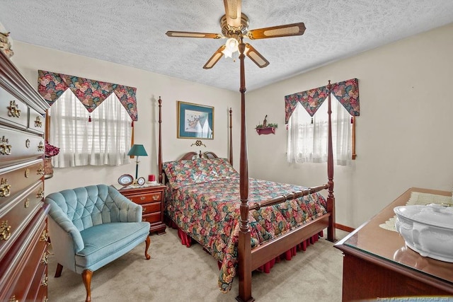 bedroom with a textured ceiling, ceiling fan, and light colored carpet