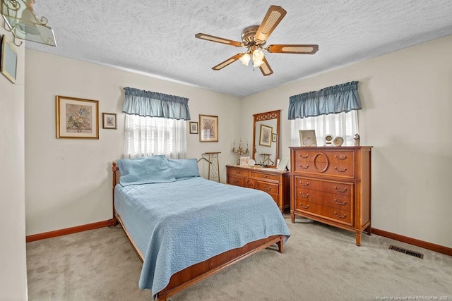 carpeted bedroom featuring ceiling fan, multiple windows, and a textured ceiling