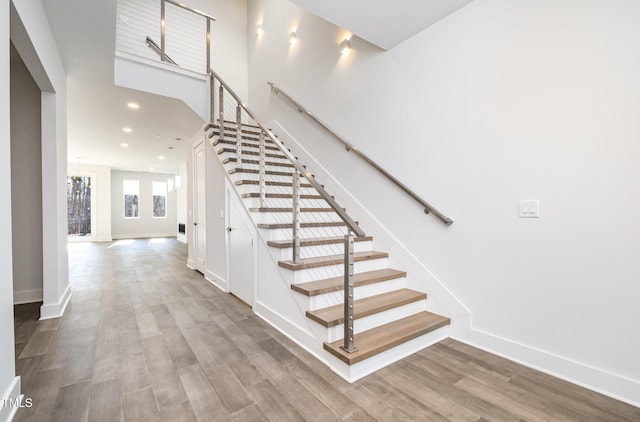 staircase with wood-type flooring and an inviting chandelier