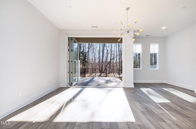 interior space with wood-type flooring, an inviting chandelier, and plenty of natural light