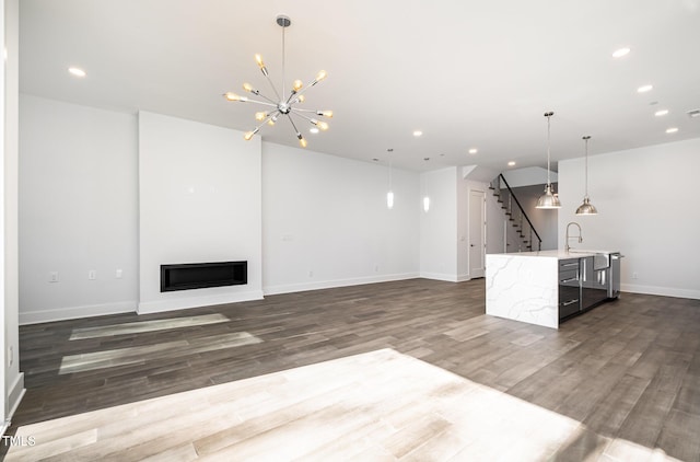 unfurnished living room featuring sink, a chandelier, and dark wood-type flooring