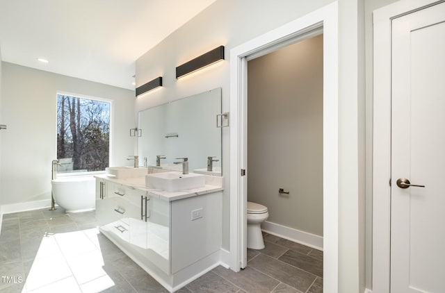 bathroom featuring tile patterned floors, toilet, vanity, and a bathing tub