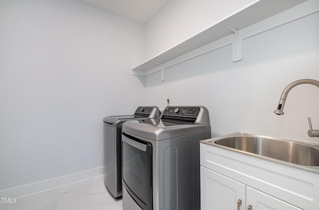 laundry room with cabinets, washer and clothes dryer, and sink