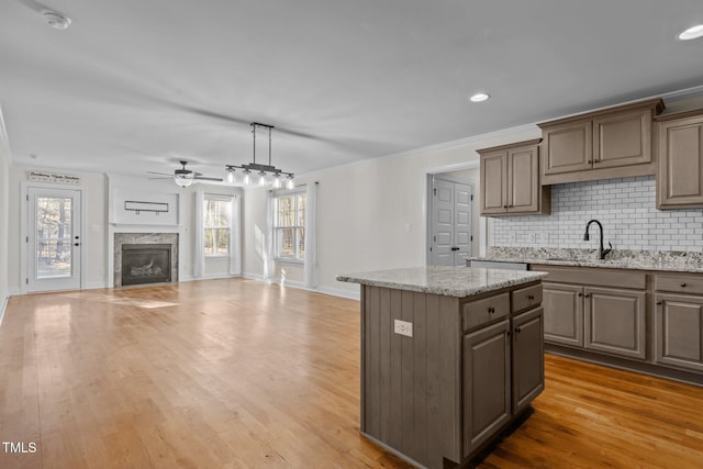 kitchen with decorative light fixtures, a center island, ceiling fan, and light hardwood / wood-style flooring