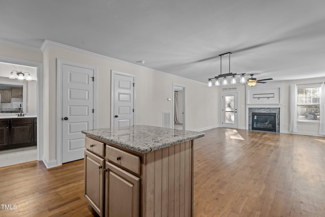 kitchen featuring hanging light fixtures, a center island, ceiling fan, a fireplace, and tasteful backsplash