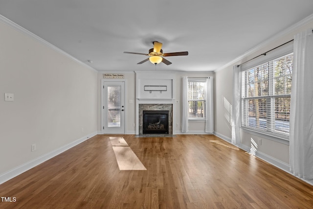 unfurnished living room featuring a high end fireplace, ceiling fan, hardwood / wood-style flooring, and crown molding