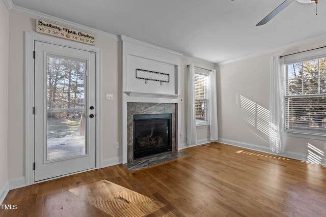 unfurnished living room with a tile fireplace, ceiling fan, ornamental molding, and wood-type flooring