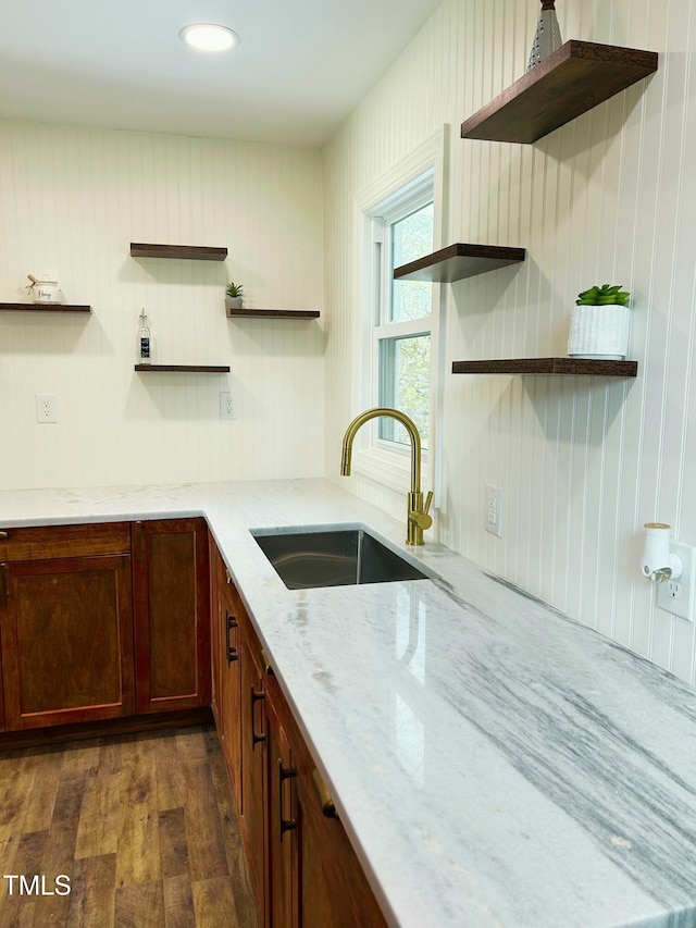 kitchen featuring light stone countertops, dark hardwood / wood-style flooring, and sink