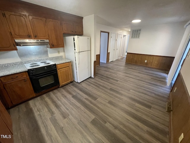 kitchen featuring dark wood-type flooring, wood walls, white fridge, and range with electric stovetop