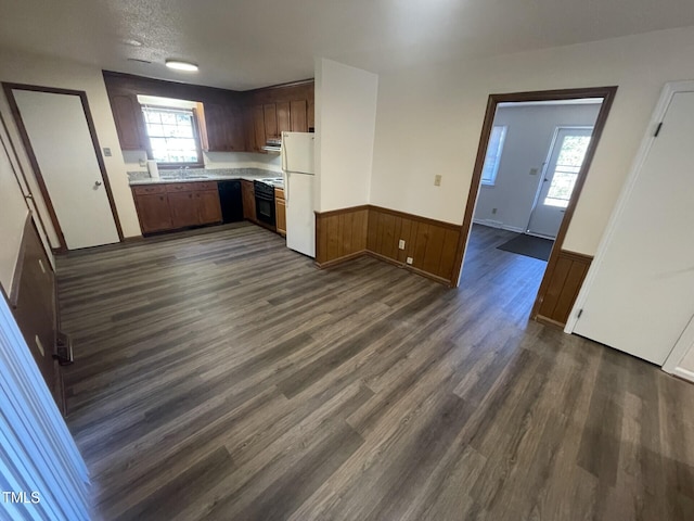 kitchen with wood walls, sink, white refrigerator, dark wood-type flooring, and a textured ceiling