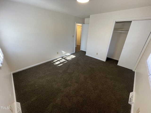 unfurnished bedroom featuring a closet and dark colored carpet