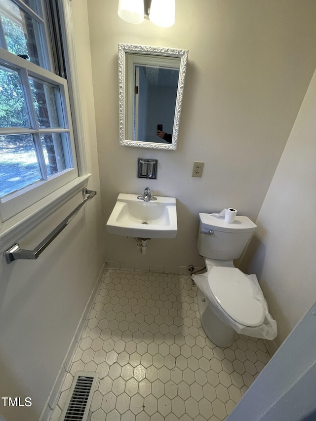 bathroom with toilet, sink, and a wealth of natural light