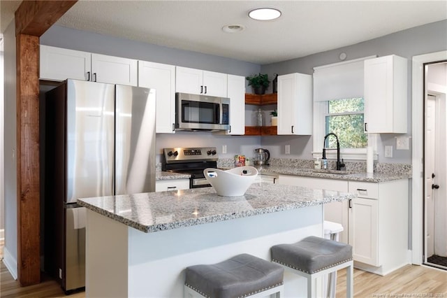 kitchen featuring a kitchen island, stainless steel appliances, white cabinetry, and a breakfast bar area