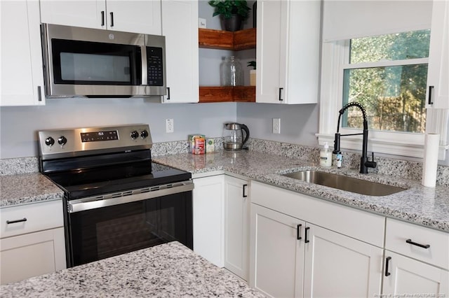 kitchen featuring light stone countertops, appliances with stainless steel finishes, white cabinetry, and sink