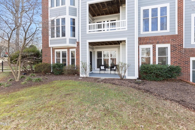 back of property featuring a balcony, a lawn, and a patio