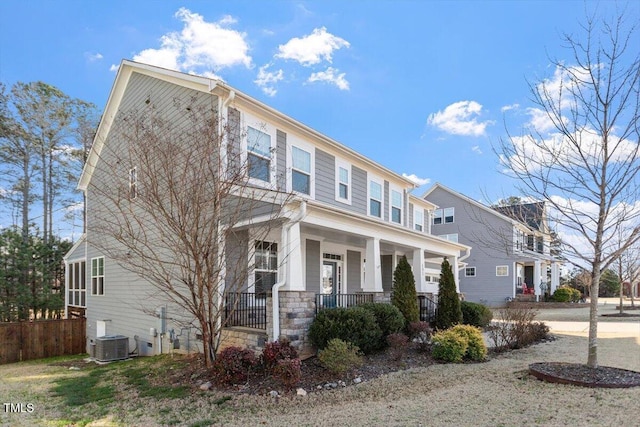 view of front of house with fence, a porch, central AC unit, and stone siding