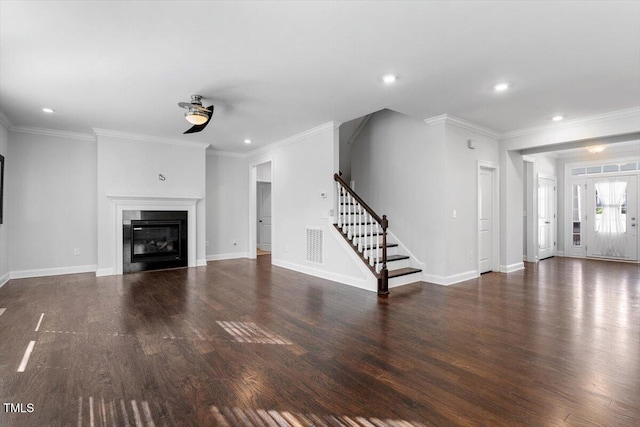 unfurnished living room featuring dark wood finished floors, crown molding, stairs, and a glass covered fireplace