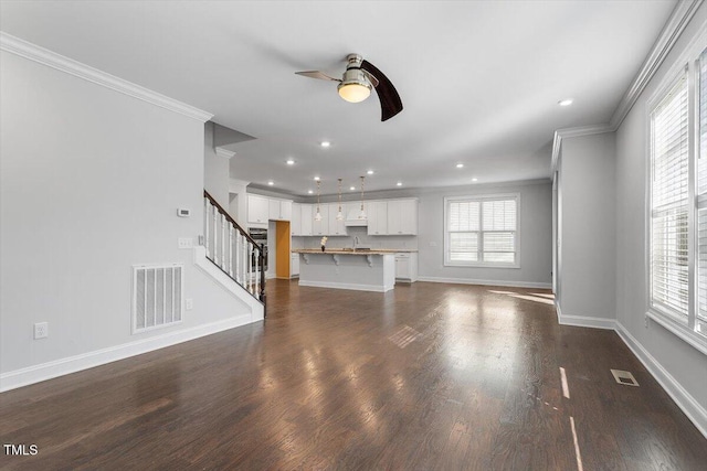 unfurnished living room featuring a wealth of natural light, visible vents, and stairway