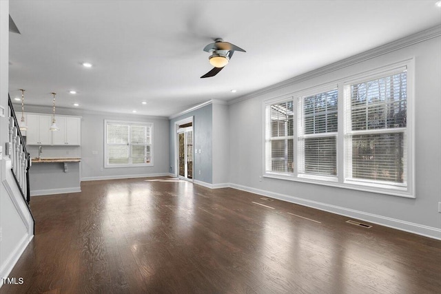 unfurnished living room featuring baseboards, visible vents, crown molding, dark wood-style floors, and a ceiling fan