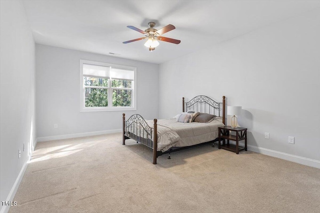 bedroom featuring baseboards, visible vents, light colored carpet, and a ceiling fan