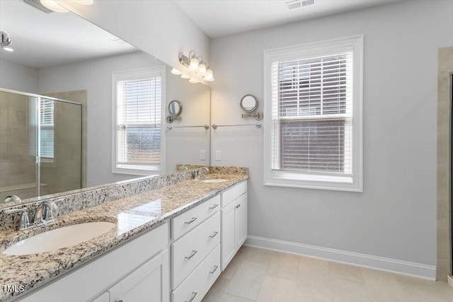 full bath featuring double vanity, a stall shower, baseboards, visible vents, and a sink