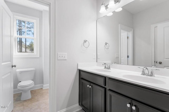 full bath with double vanity, toilet, a sink, and baseboards